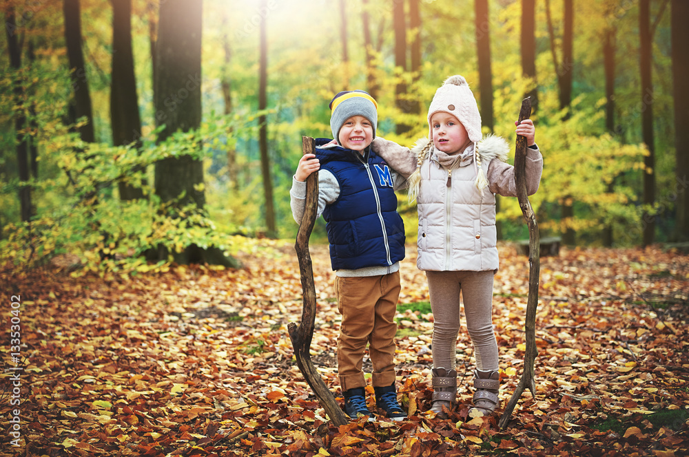 Two hugging children holding branches in forest