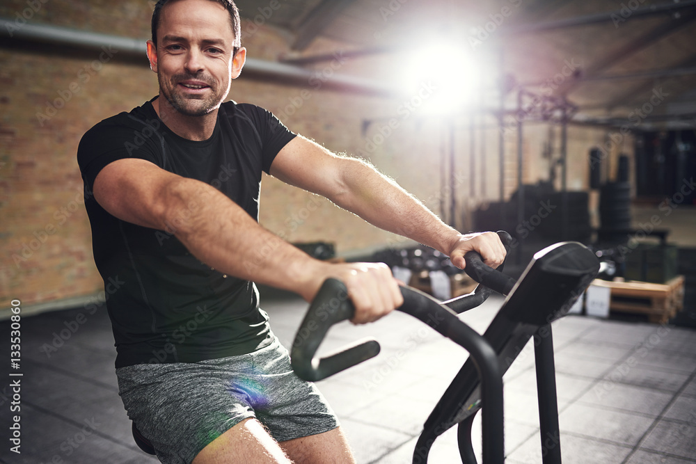 Young smiling man training on cycling machine