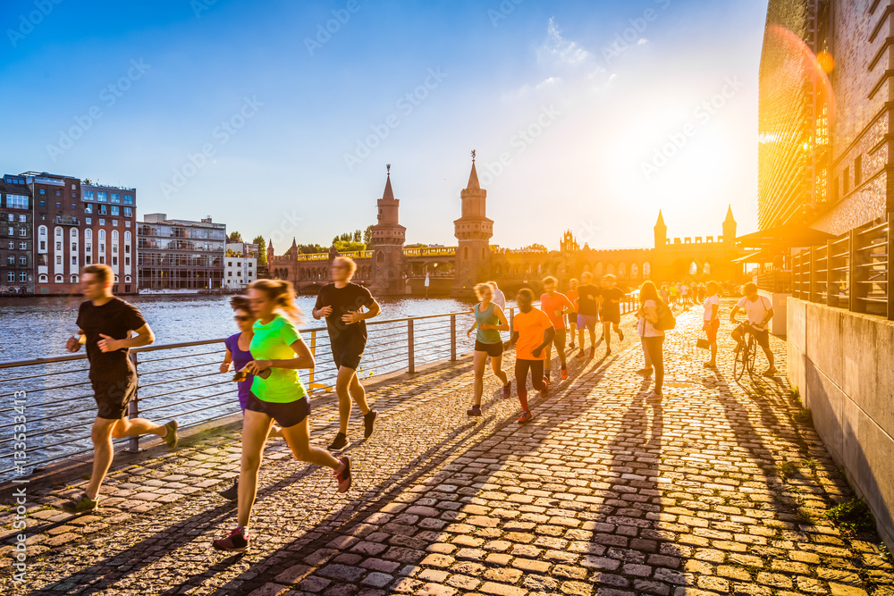 Group of female and male runners jogging in urban area at sunset