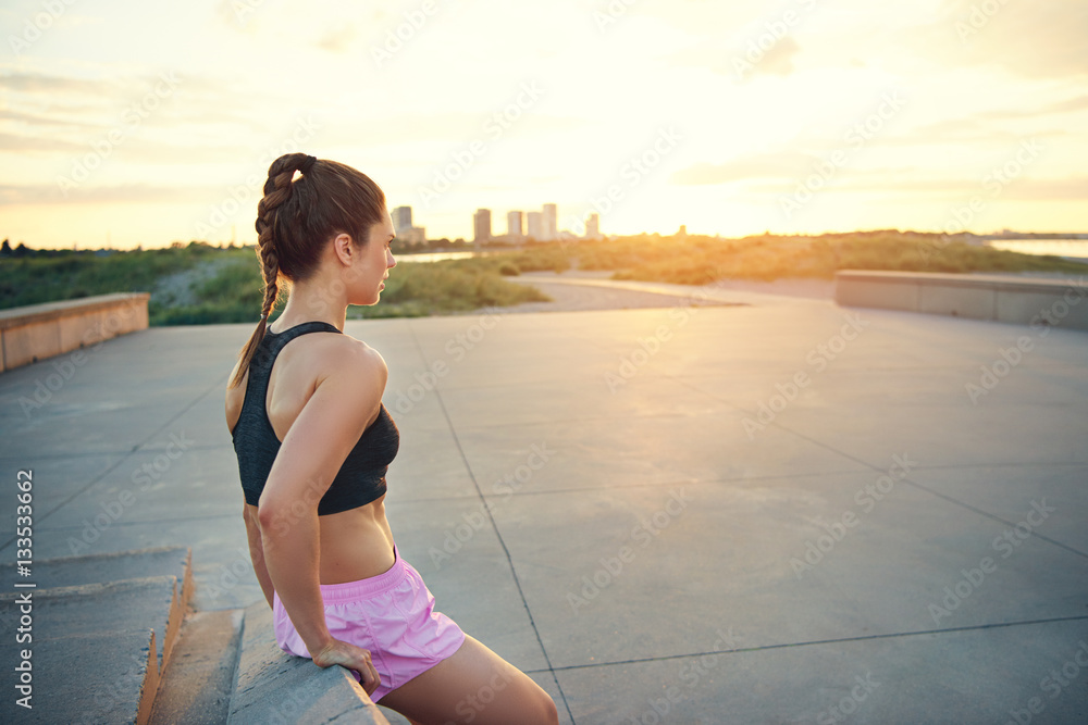 Young female athlete leaning on bench