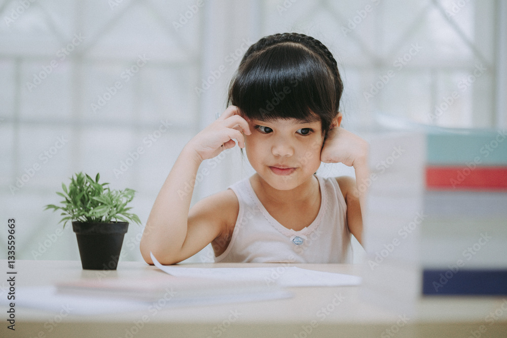 Decent school child. holding her head with a hand and reading a book