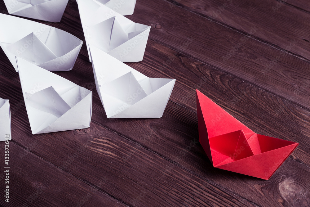 Business leadership concept with white and color paper boats on 