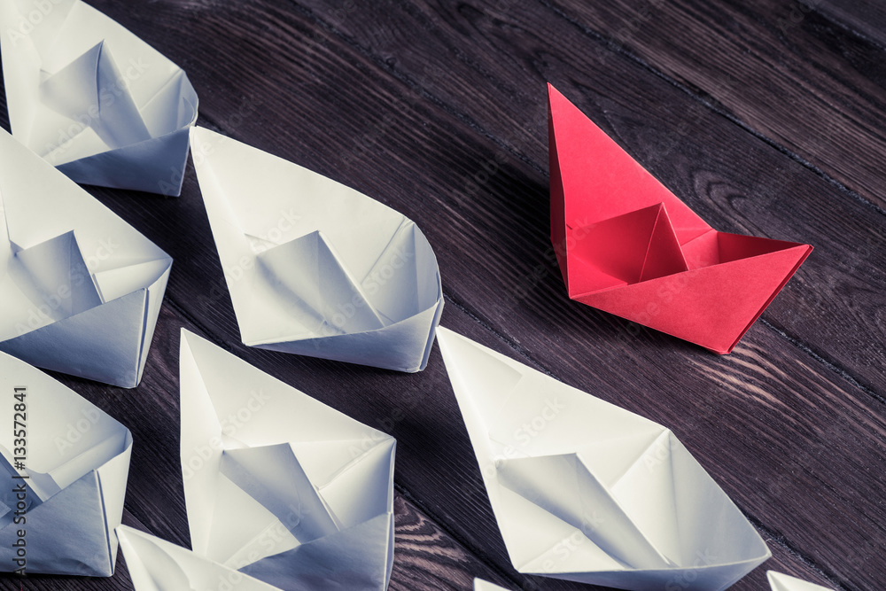 Business leadership concept with white and color paper boats on 