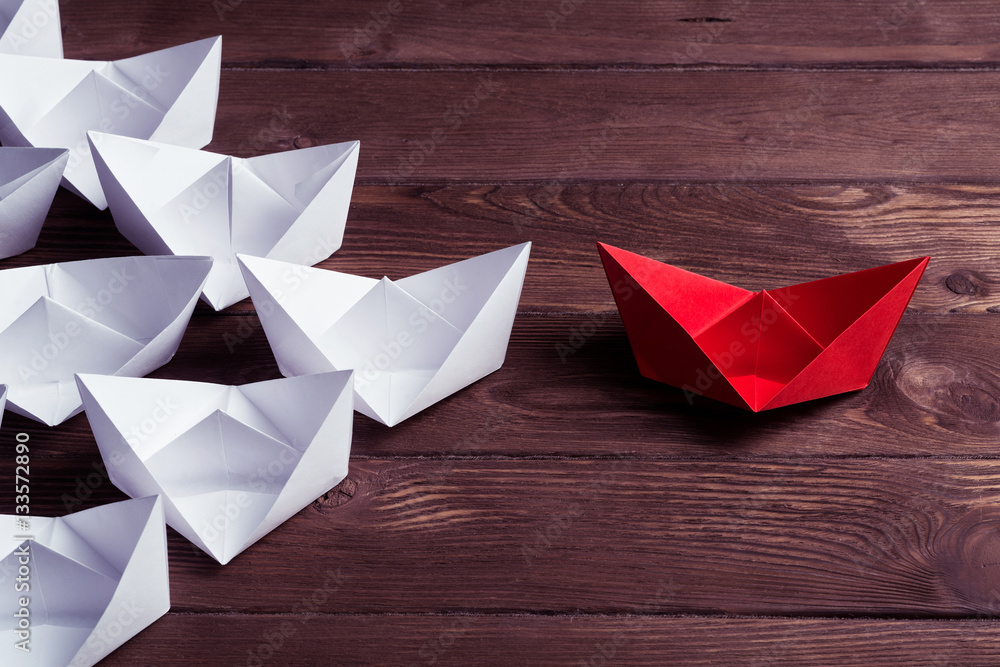 Business leadership concept with white and color paper boats on 