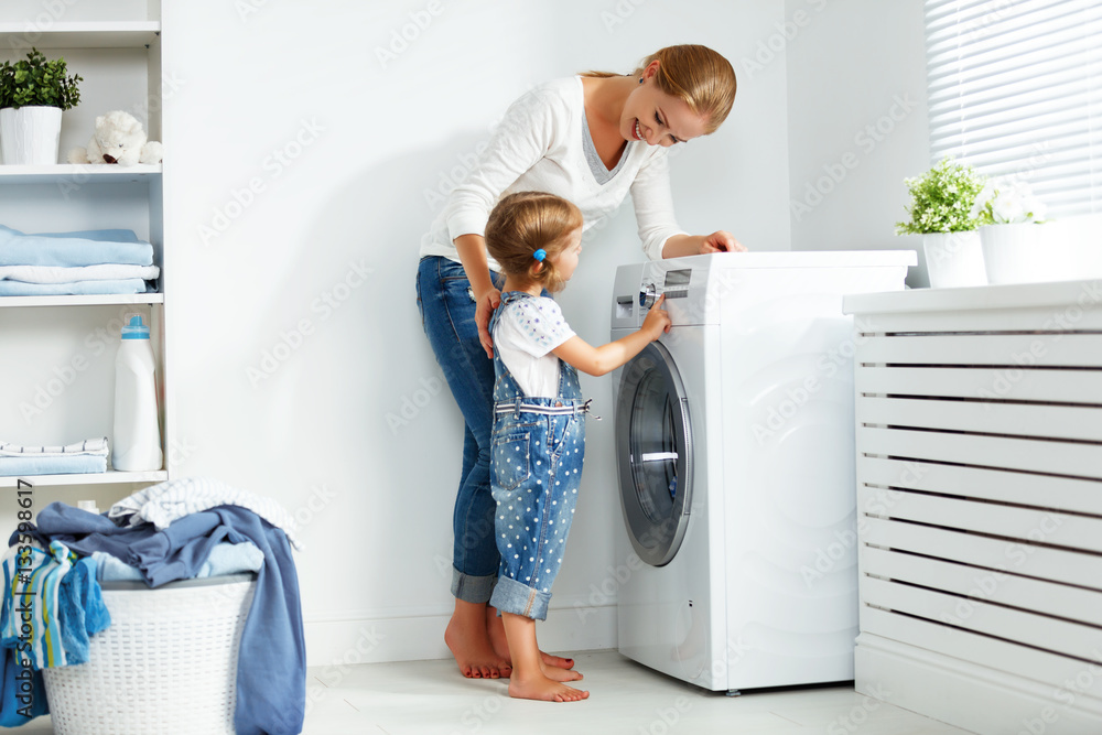 family mother and child girl  in laundry room near washing machi