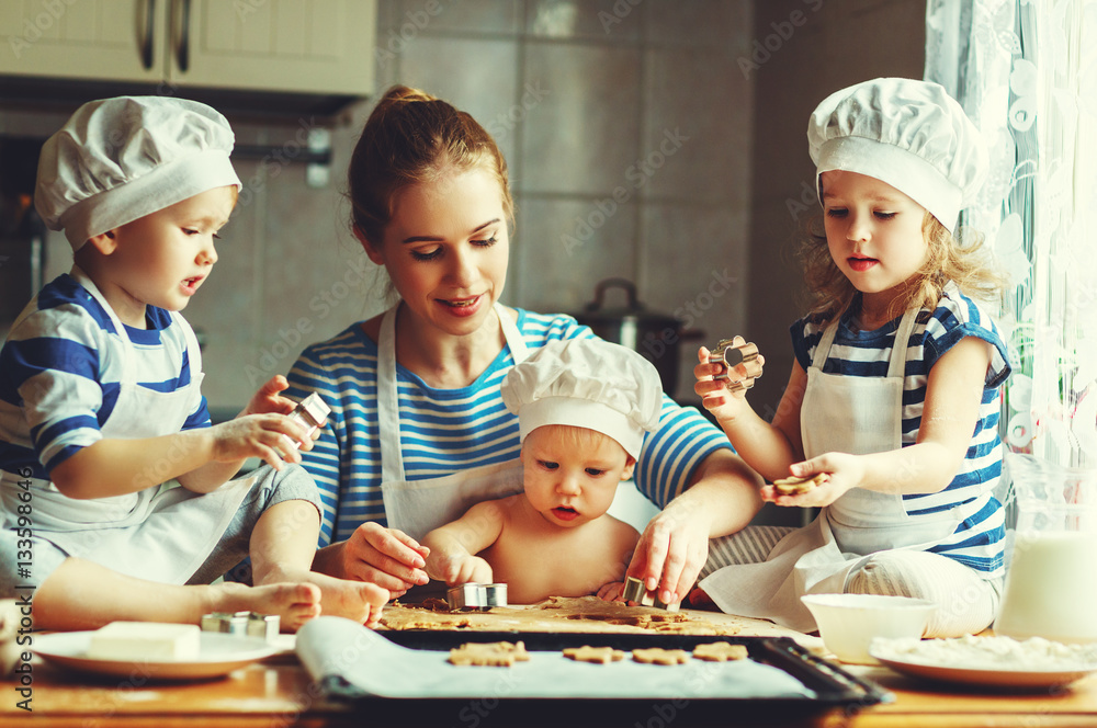 happy family in kitchen. mother and children preparing dough, ba