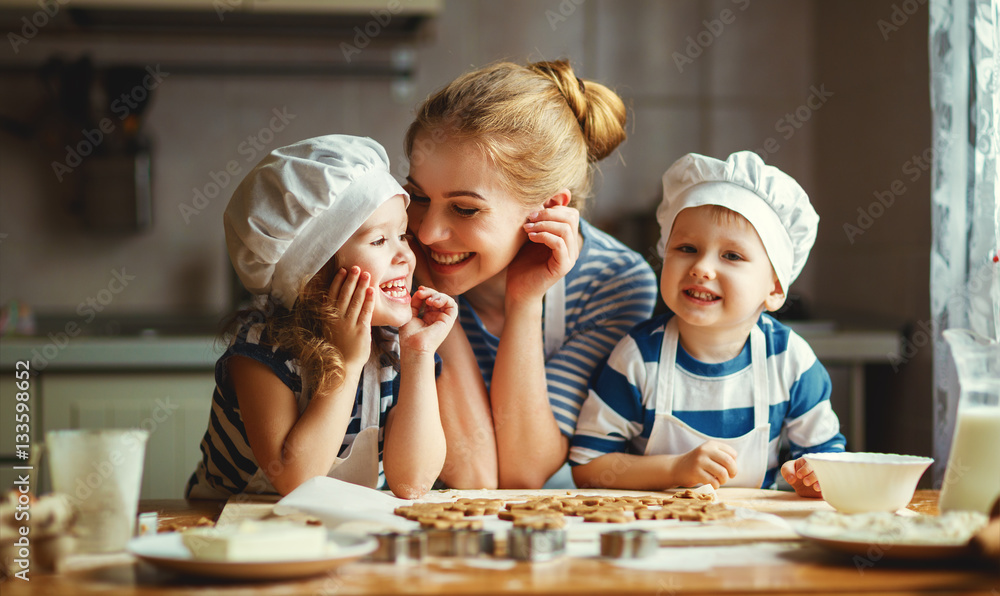 happy family in kitchen. mother and children preparing dough, ba