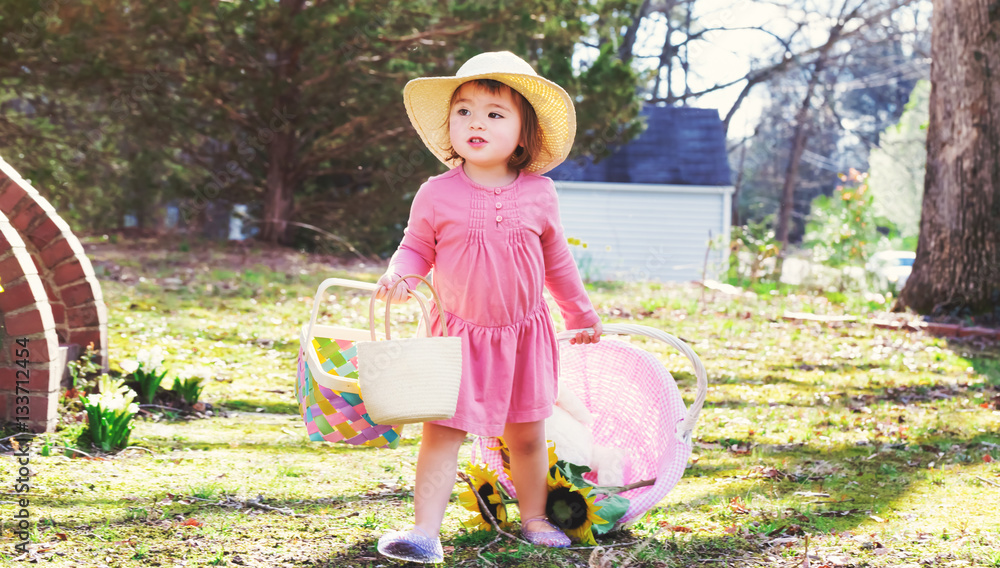 Toddler girl playing outside with an Easter basket