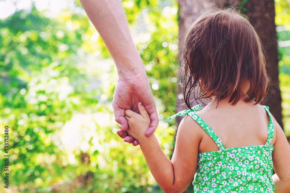 Toddler girl holding hands with her mother