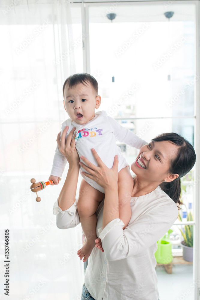 Portrait of happy asian mother and baby having fun together at h