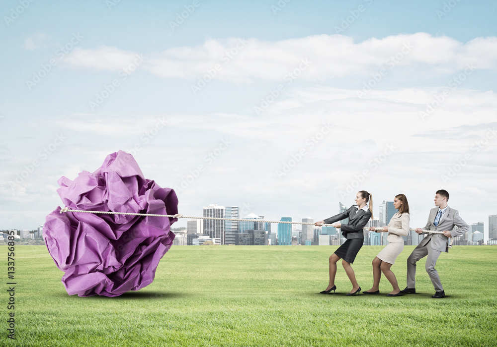 Young business people outdoors and huge paper ball as symbol of creativity