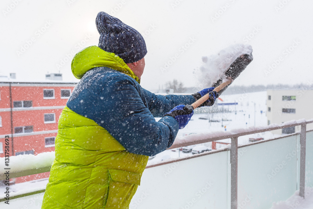 Man shoveling the show on the terrace after heavy snowfall