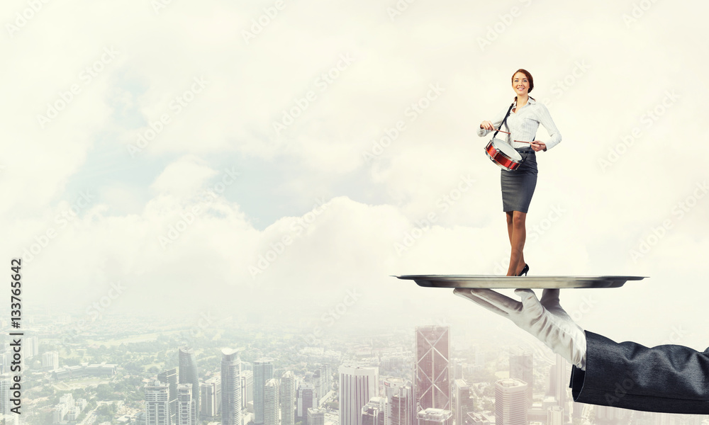 Attractive businesswoman on metal tray playing drums against cityscape background