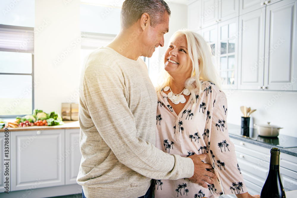 Senior male embracing woman in kitchen