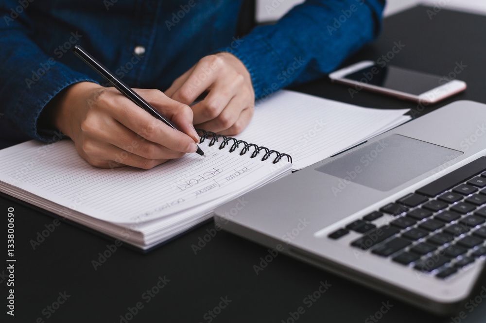 Female hands with pen writing report on notebook