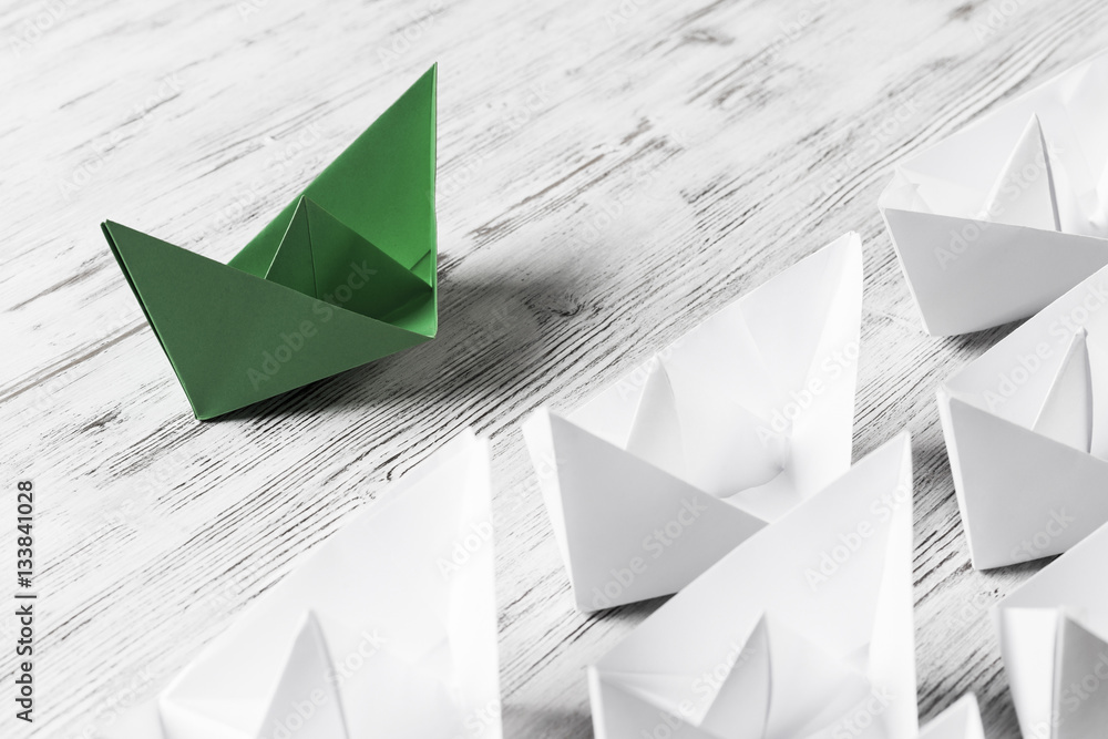 Business leadership concept with white and color paper boats on 