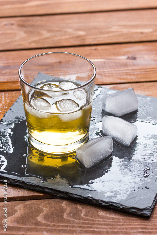 glass of whiskey on wooden background