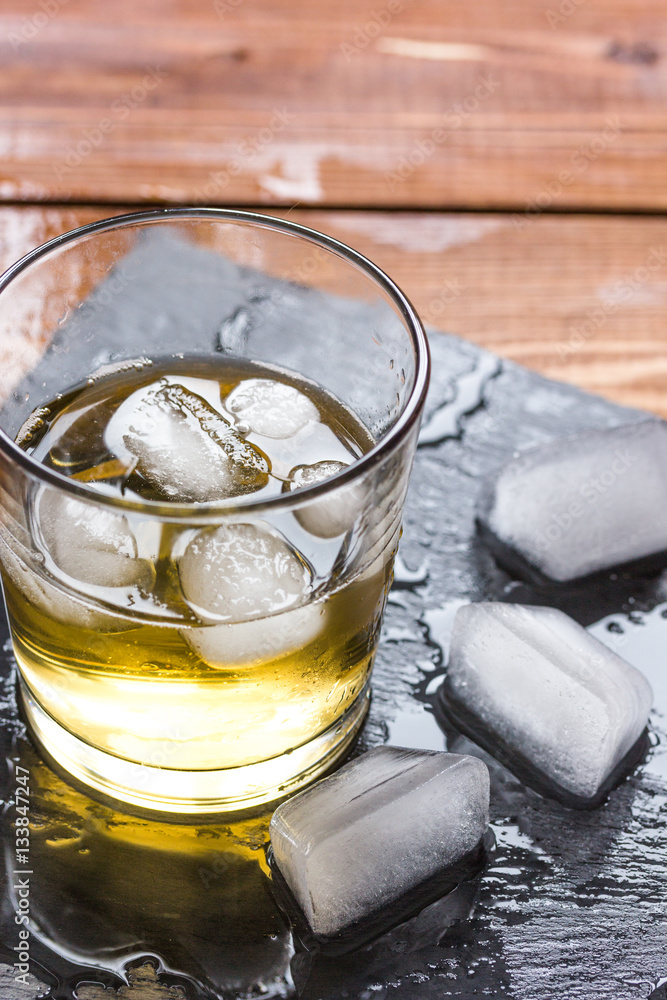 glass of whiskey on wooden background