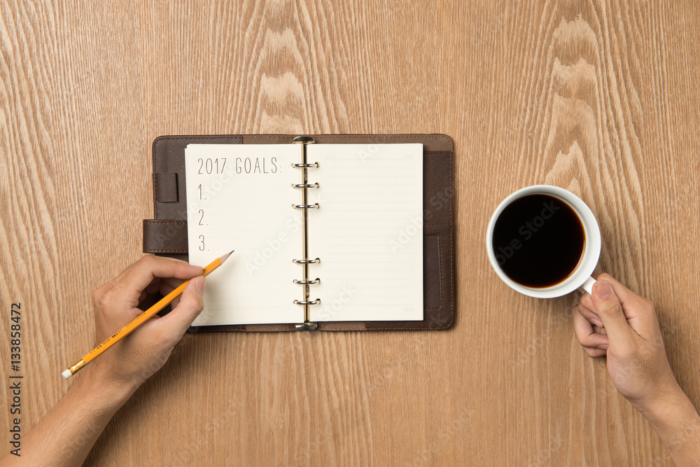 2017 Goals.. Top view of hand writing on a blank notebook with h