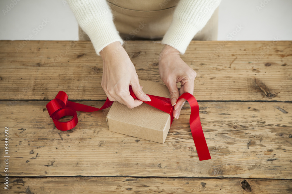 Women are tying a red ribbon on the box