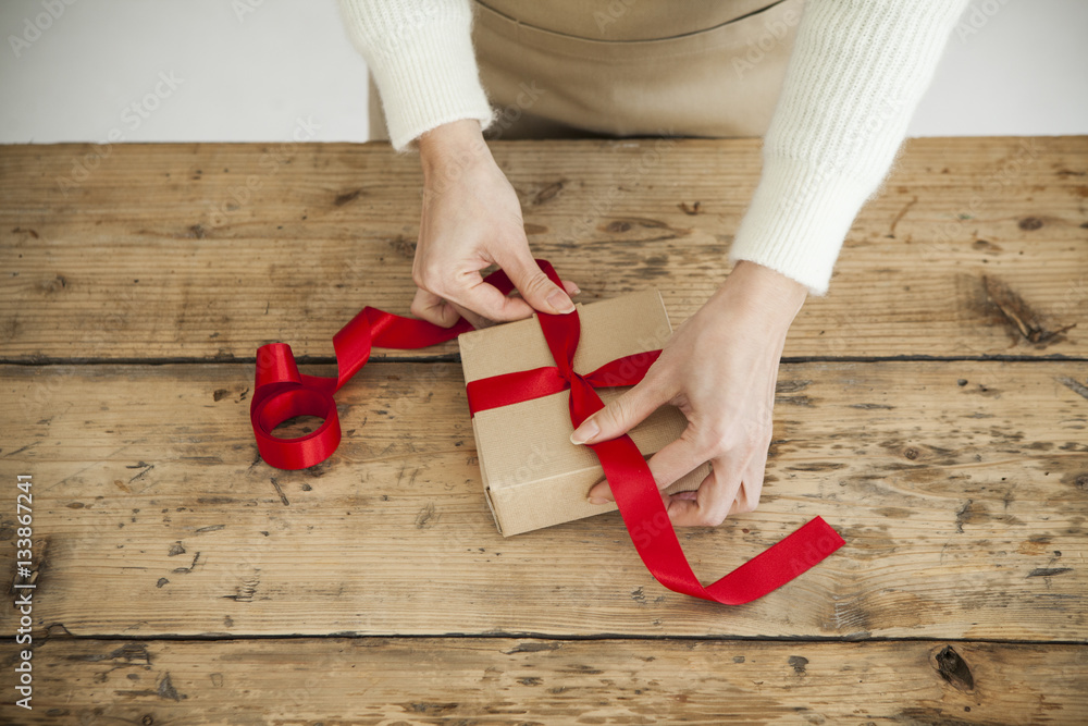 Women are tying a red ribbon on the box