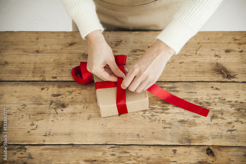 Women are tying a red ribbon on the box