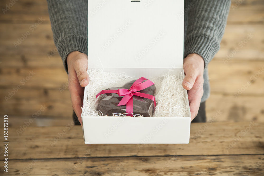 Male hands heart-shaped chocolate cake to lover