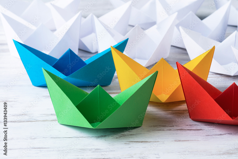 Business leadership concept with white and color paper boats on 