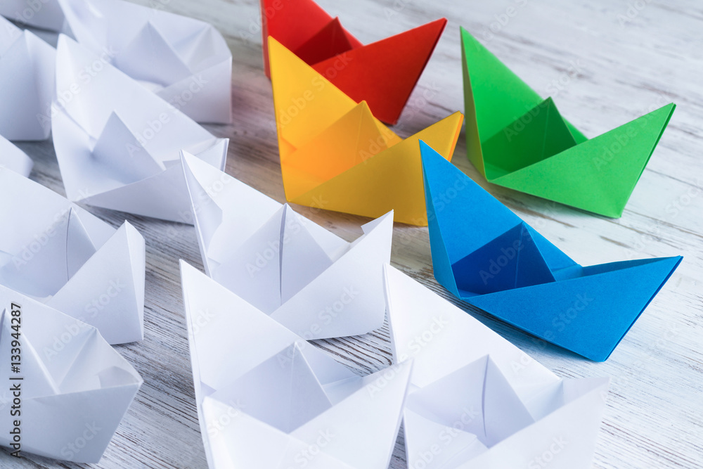 Business leadership concept with white and color paper boats on 