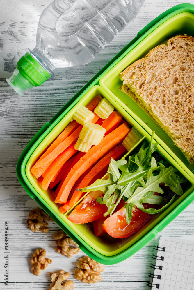 green lunch box for kid on wooden background top view