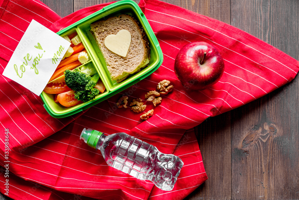 green lunch box for kid on wooden background top view