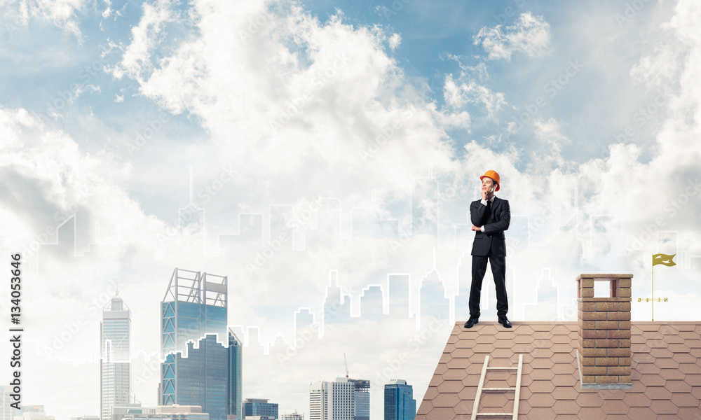 Engineer man standing on roof and looking away. Mixed media