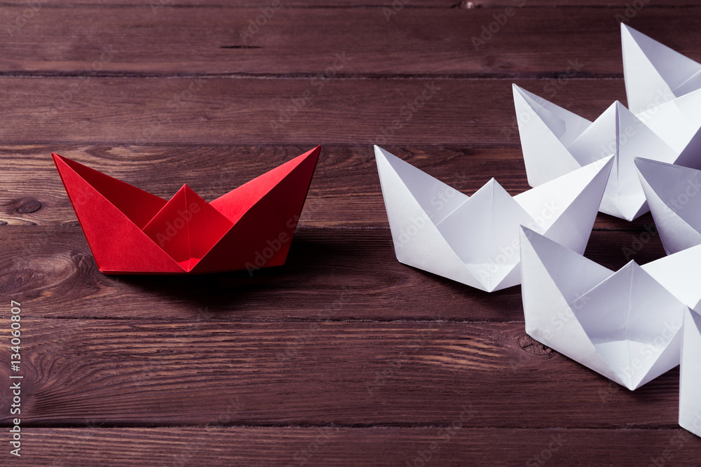 Business leadership concept with white and color paper boats on 