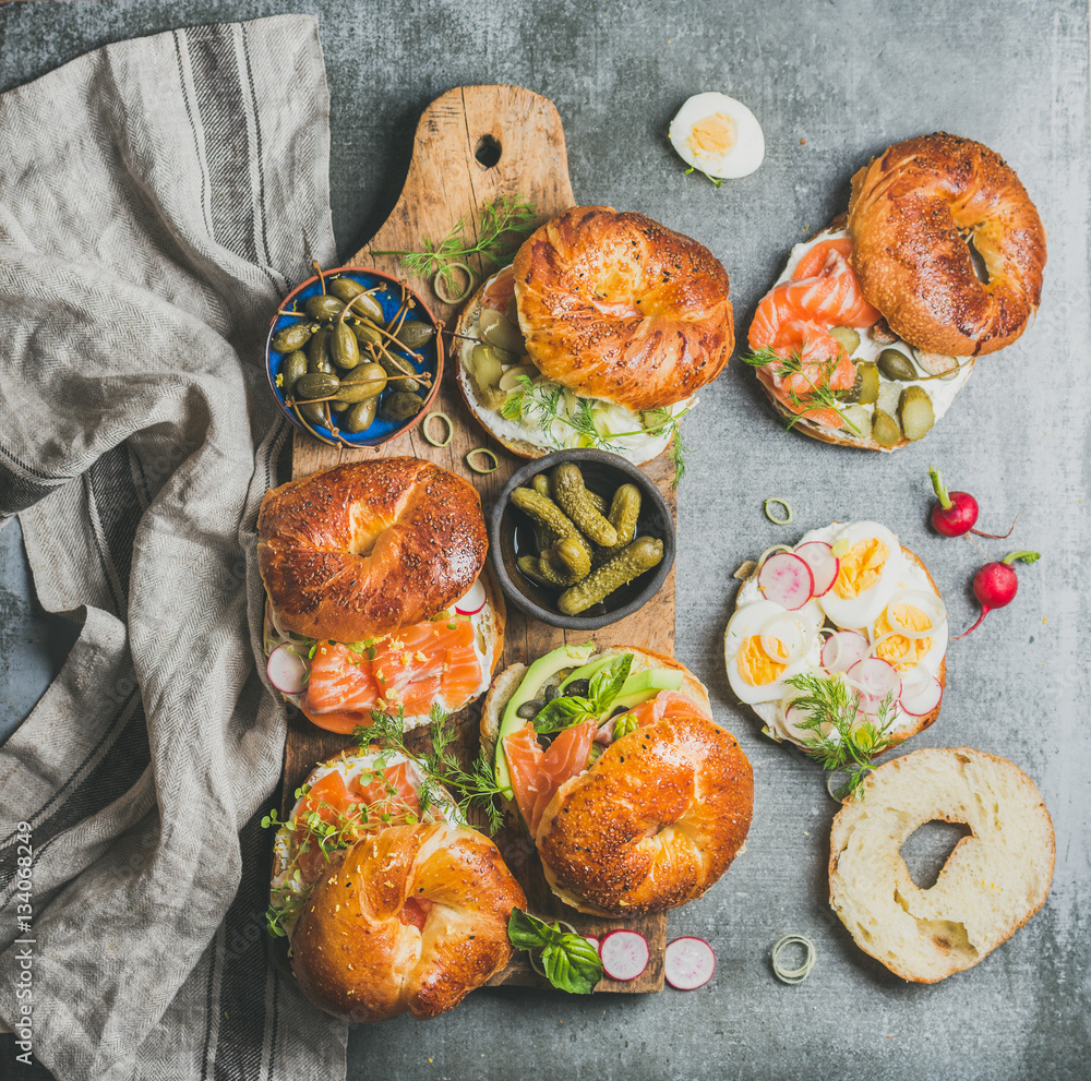 Variety of bagels with smoked salmon, eggs, radish, avocado, cucumber, greens and cream cheese for b