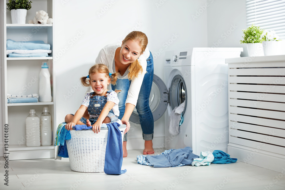 family mother and child girl  in laundry room near washing machi