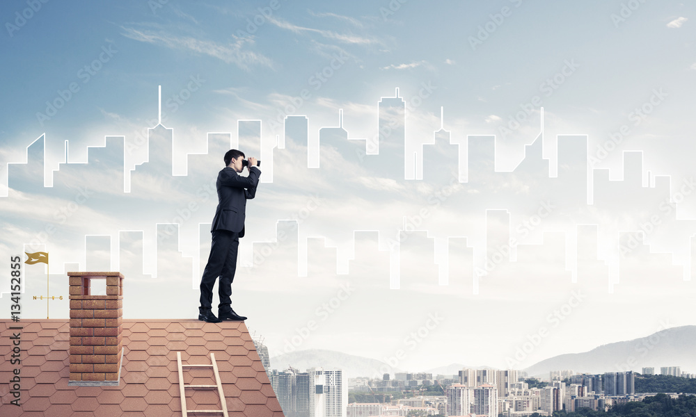 Businessman standing on roof and looking in binoculars. Mixed me