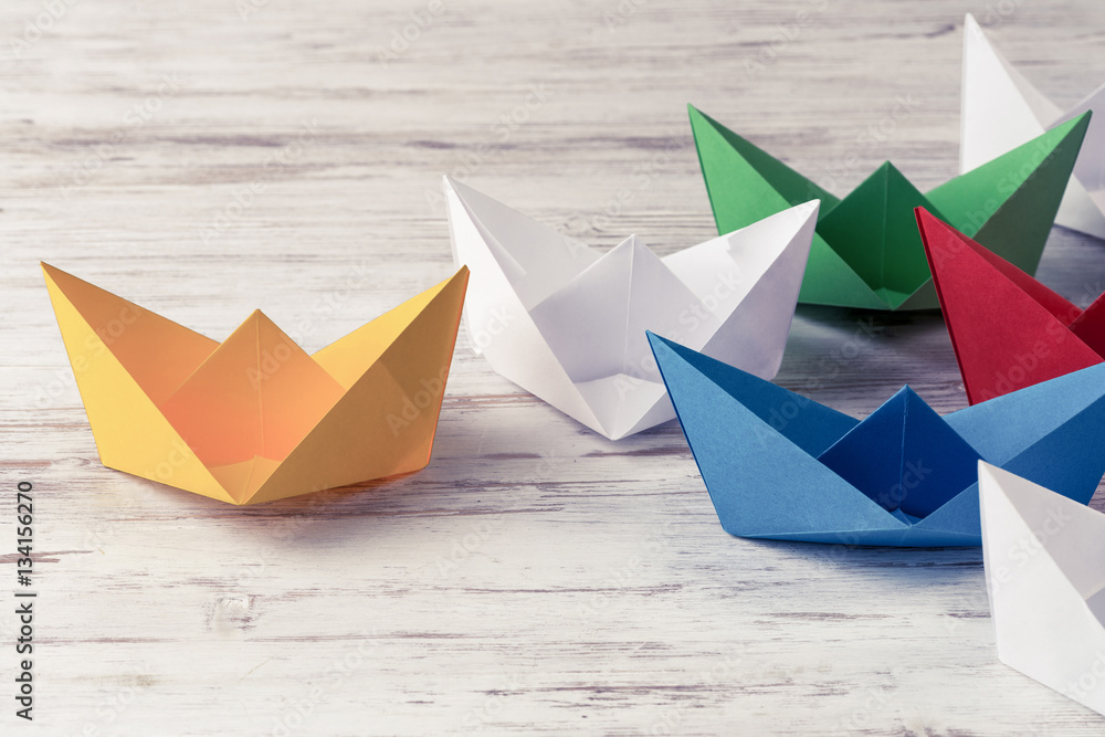 Business leadership concept with white and color paper boats on 