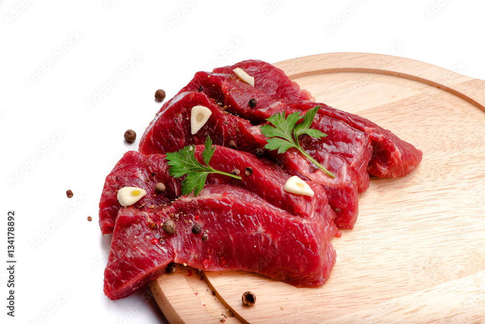 Pieces of meat with garlic and parsley on wooden board isolated. Raw beef. Top view.