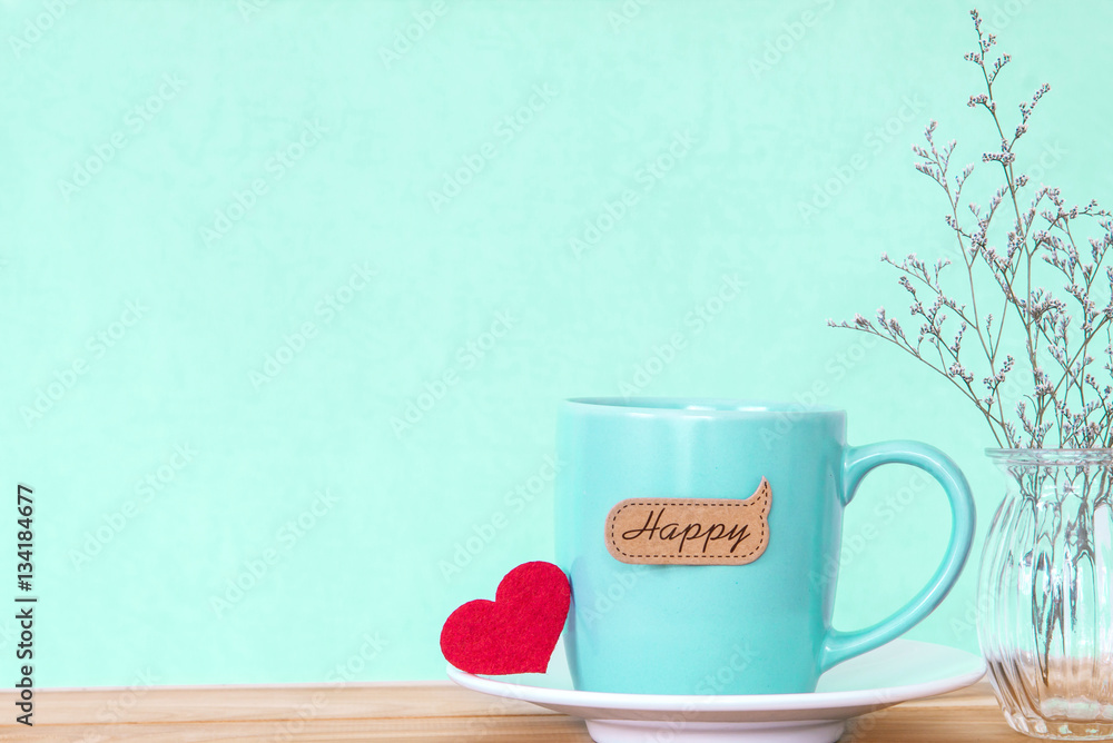 Coffee cup mug with red heart shapeand happy word tag on wooden