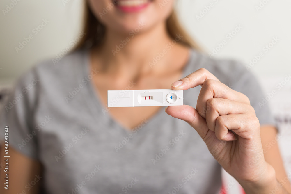 happy smiling asian woman holding and showing positive home preg