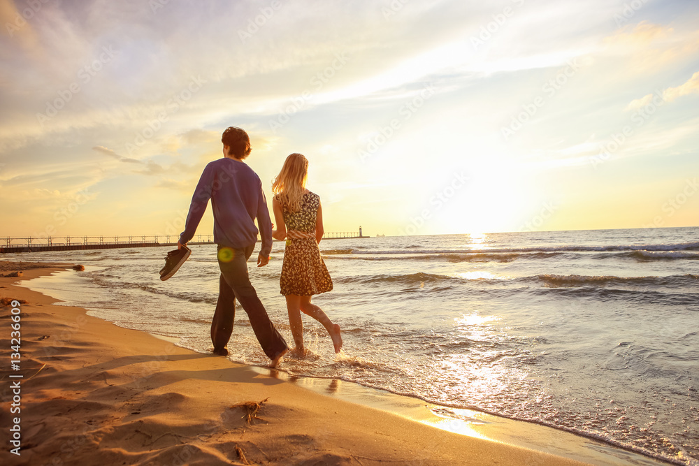 Couple walking on the beach at sunset