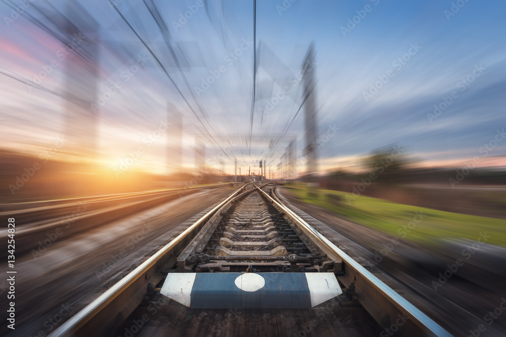 Railroad in motion at sunset. Railway station with motion blur effect against colorful blue sky, Ind