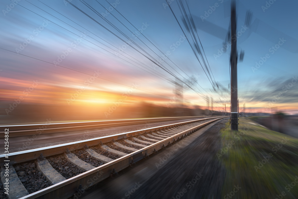 Railroad in motion at sunset. Railway station with motion blur effect against colorful blue sky, Ind