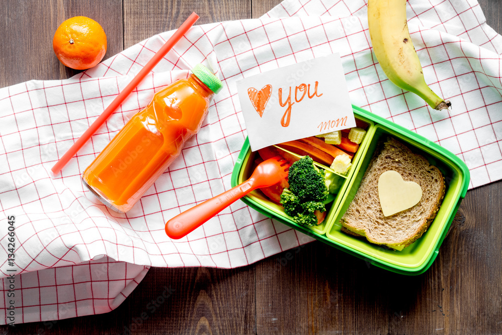 green lunch box for kid on wooden background top view