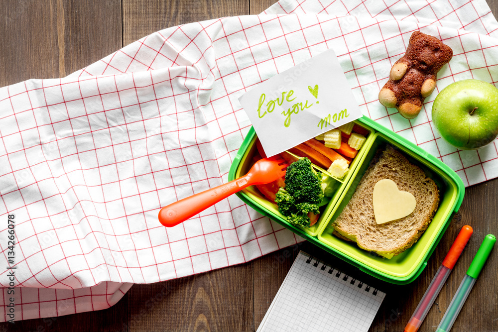 green lunch box for kid on wooden background top view