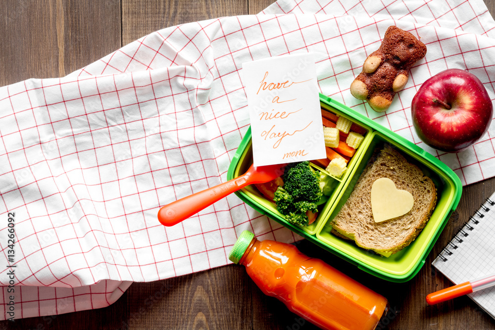 green lunch box for kid on wooden background top view