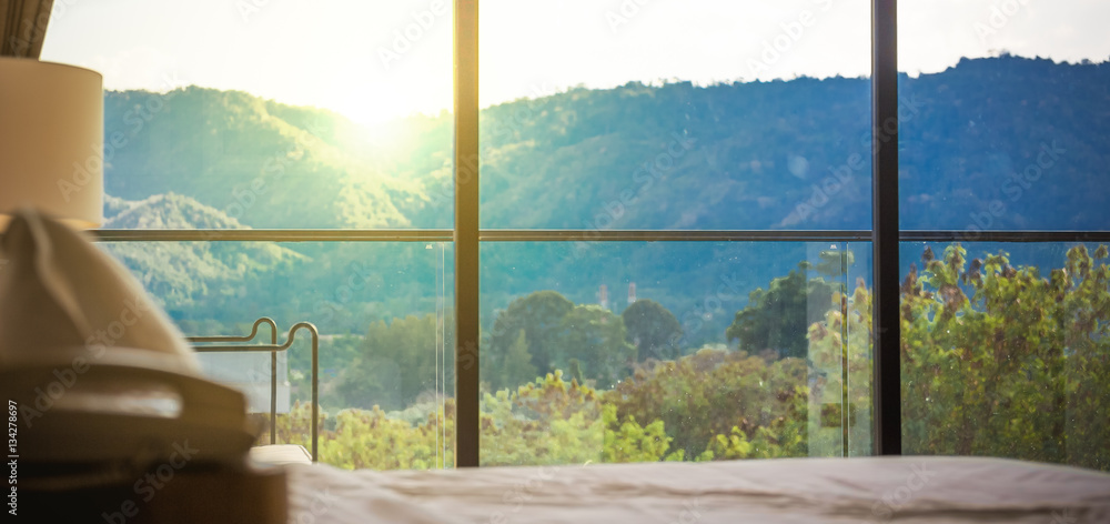 looking through big window at beautiful foggy hills with colorful sunset.