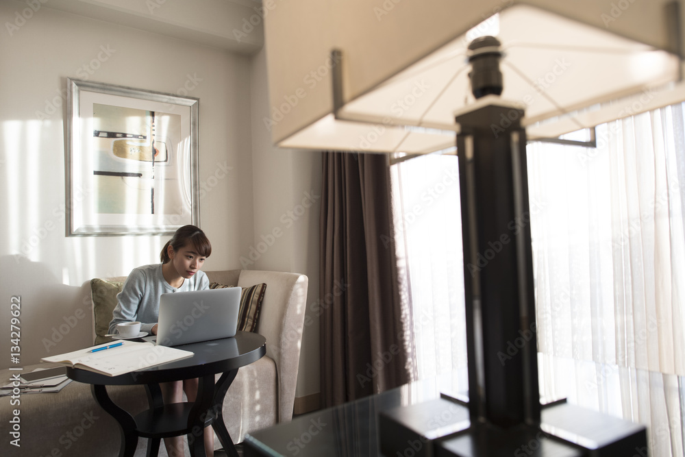 The lady is using a laptop computer in the hotel room