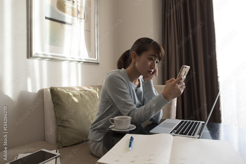 A young lady is crazy about a smartphone in a hotel room