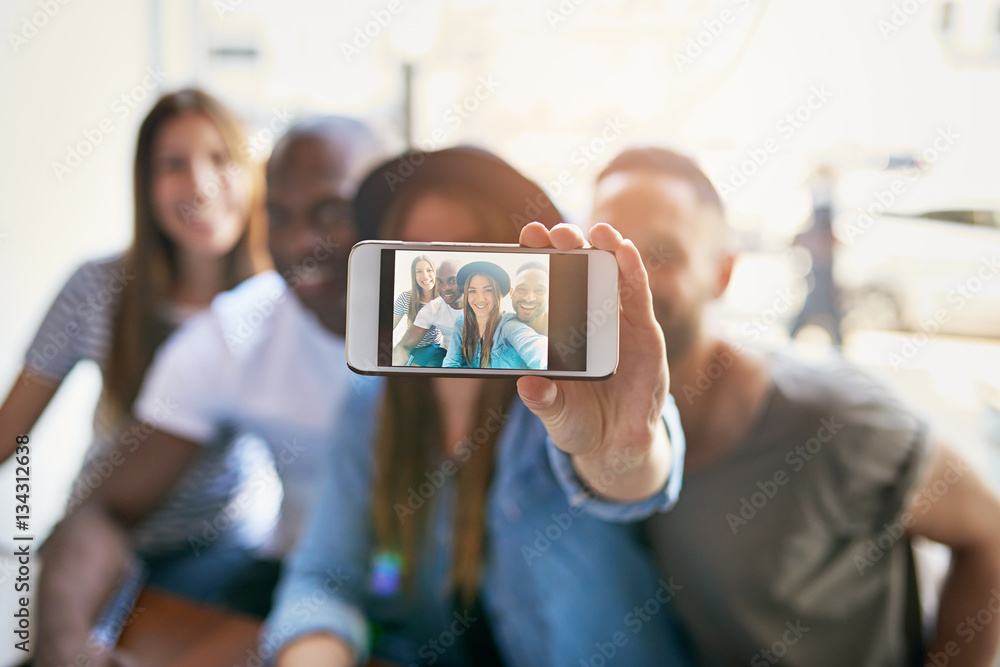 Girl taking self portrait with three friends